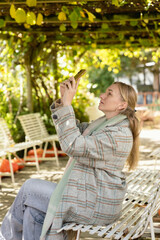 A young beautiful woman walks through the autumn park. A girl with a smartphone takes photos in an autumn forest