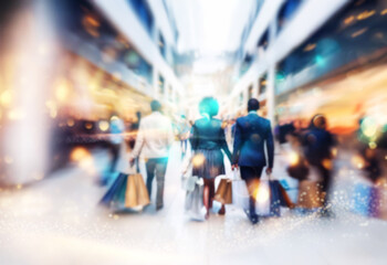 Naklejka premium Blurred motion of people walking through an indoor shopping mall with bags.