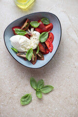 Italian caprese with buffalo mozzarella and heirloom tomatoes, vertical shot on a beige stone background, view from above