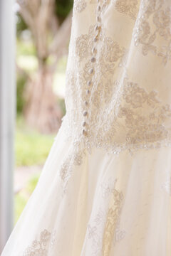 wedding dress details including buttons and lace with a garden behind