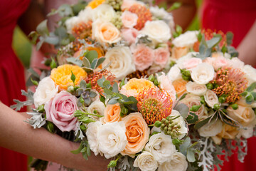 bouquets of wedding flowers in white, orange and other pastel tones with foliage