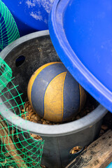 The old volleyball ball was stored for a long time in a black plastic container behind the house.