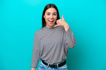Young caucasian woman isolated on blue background making phone gesture. Call me back sign