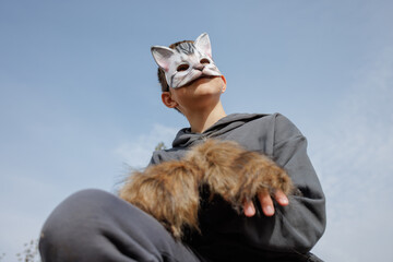 A catmasked teenager performs Quadrobics with gloves mimicking a felines movements