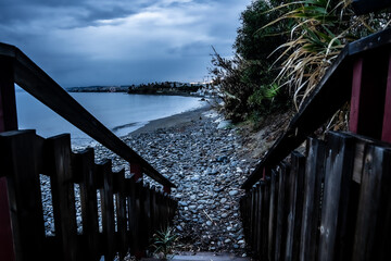 Escalera de madera que lleva hacia la playa un día nublado