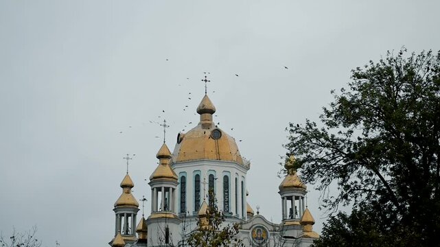 Tample against sky with birds circling around. A disturbing scene with birds