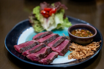 Medium rare sliced Picanha steak meat served on plate with vegetable