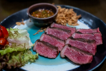 Medium rare sliced Picanha steak meat served on plate with vegetable