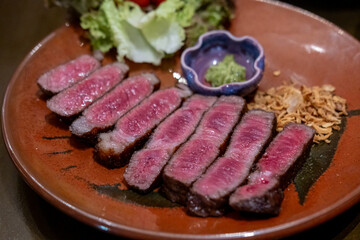 Medium rare sliced rib eye meat served on plate with vegetable