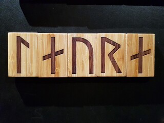 The name Laura written in runic characters engraved on wooden tablets.