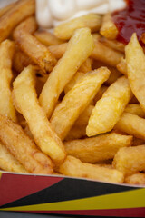 Belgian street and fast food, paper box in colors of Belgian flag with fried potato frit chips and ketchup and mayonnaise sauсe