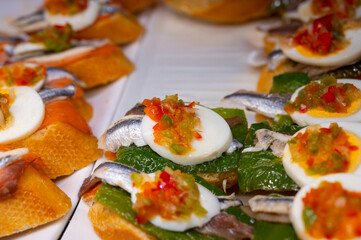 Typical snack of Basque Country, pinchos or pinxtos skewers with small pieces of bread, sea food, eggs, cheese, jamon served in bar in San-Sebastian or Bilbao, Spain, close up