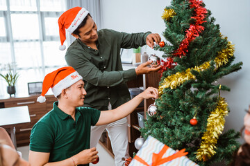 Two close friends joyfully celebrate the holiday season by adorning their beautiful Christmas tree