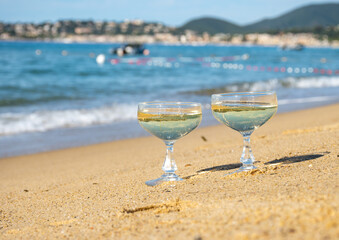 Summer time on French Riviera, two coupe glasses of champagne cremant sparkling wine on Pampelonne sandy beach near Saint-Tropez in sunny day, Var, vacation in France