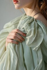 Naklejka premium Soft Fabric Drapery: A Close-Up of a Woman's Hand Holding Delicate, Light Green Chiffon, Perfect for Fashion or Beauty Themes