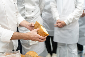 The teacher shows the students bread in a cut. A lesson or master class at a bakery factory.