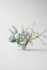 Elegant floral arrangement featuring blue and white blooms in a delicate vase against a minimalist background
