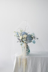 Beautiful arrangement of blue and white flowers in a stylish vase on a table against a light background