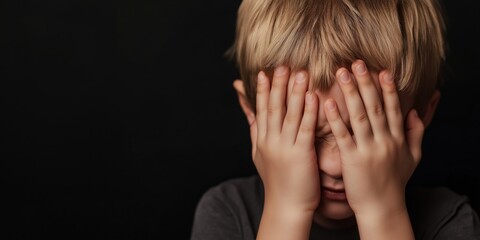 A child with hands covering their face shows sadness against a dark backdrop, highlighting themes of emotion, vulnerability, and human experience in a simple scene.