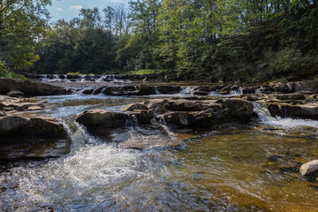 Small cascade waterfall on a mountain river in sunny day