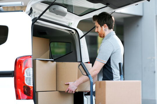 Professional delivery man loading packages on a hand truck