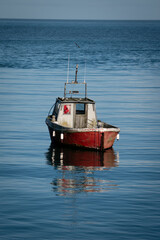 Little lone red sailboat isolated in peaceful serene blue sea