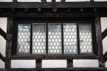 Historic old wooden window frames with glass reflection in historic tudor building