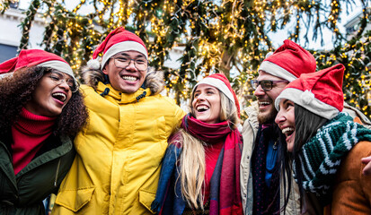 Happy friends wearing santa claus hat celebrating Christmas day in city street - Winter holidays life style concept