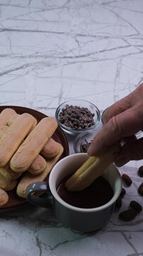 Uomo inzuppa un biscotto nella cioccolata calda, piatto con biscotto e cioccolata in pezzi nelle ciotole, video verticale