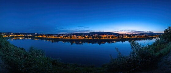 Obraz premium Nighttime cityscape reflected in a tranquil river