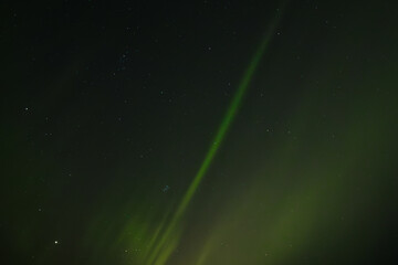  Soft green aurora borealis streaks gently across a starry night sky, creating a serene and celestial scene. Distant stars twinkle through the faint glow of the northern lights.