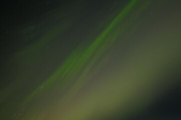  Soft green aurora borealis streaks gently across a starry night sky, creating a serene and...