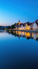 Fototapeta premium Cityscape with buildings and church reflected in still water at dusk