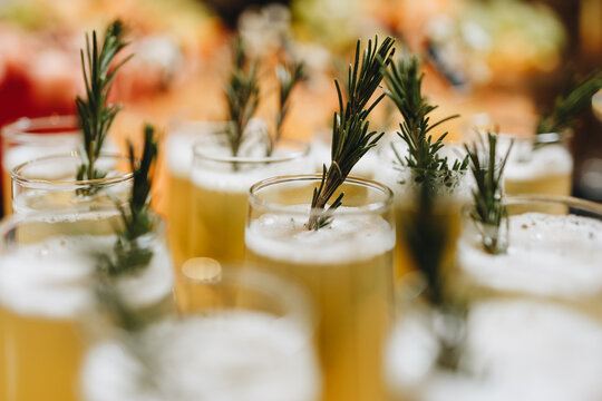 Beautiful line of different colored alcohol cocktails with mint oin the restaurant, tequila, martini, vodka, and others on decorated catering bouquet table on open 