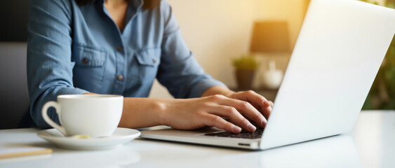 Person typing on a laptop with a coffee cup beside them, set in a bright and modern workspace. The image emphasizes productivity and a comfortable working environment.