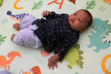Naklejka premium adorable asian baby boy sleeping on mattress 