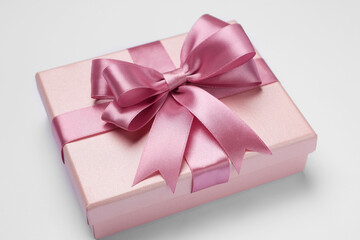 Gift box with pink bow on light grey background, closeup