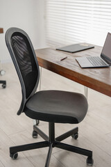Black chair, laptop and desk in office