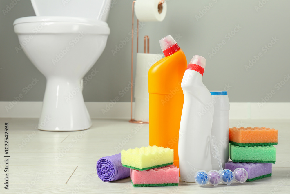 Poster Toilet cleaners, sponges and trash bags on floor in bathroom, closeup