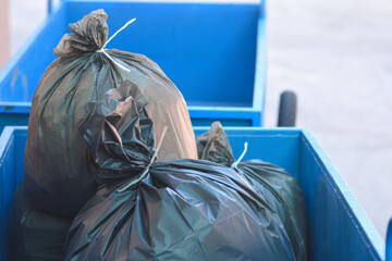 Black garbage bag in a blue cart