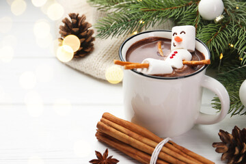 Funny snowman made with marshmallows in cup of hot chocolate and winter decor on white table
