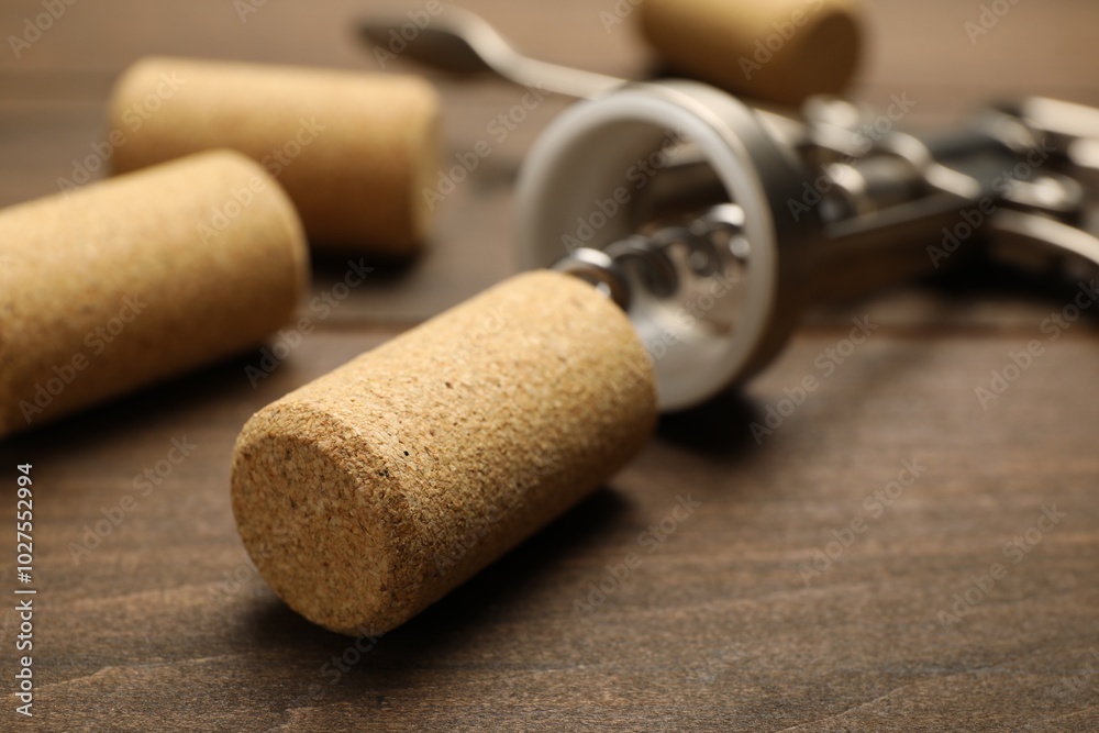 Poster Wing corkscrew and corks on wooden table, closeup