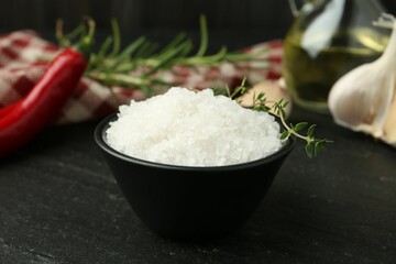 Sea salt and thyme in bowl on dark gray textured table, closeup