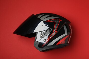 Modern motorcycle helmet with visor on red background, top view