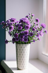 A bouquet of purple chrysanthemums stands in a vase. 