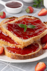 Bread with tasty strawberry jam on grey table
