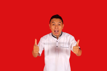 Excited Asian man wears black clothes, gives thumbs up hand gesture of approval, isolated by white...