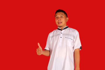 Excited Asian man wears black clothes, gives thumbs up hand gesture of approval, isolated by white...