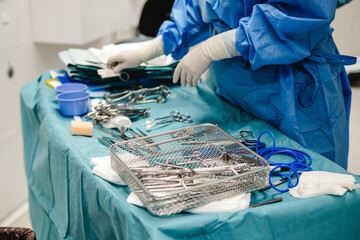 A surgeon organizing medical tools and preparing for surgery in a hospital operating room.