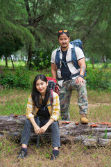 Young asian couple hikers trekking in mountains. Young couple walking with backpacks in forest. People hipster hiking on mountain holiday, wild adventure. Travel concept	